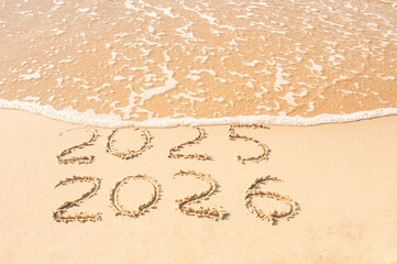 Inscription 2025 and 2026 numbers written on sand.  New Year 2025 replace 2026. Concept on the sea...