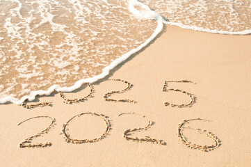 Inscription 2025 and 2026 numbers written on sand.  New Year 2025 replace 2026. Concept on the sea...