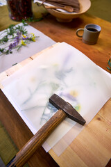 Wildflowers arranged under parchment paper, ready for botanical hammer art. Floral imprint...