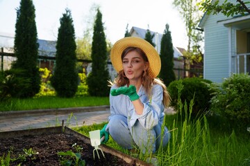 Portrait of a smiling gardener woman in the garden, preparing the soil and loosening it with a tool...