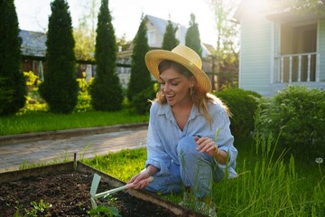 Portrait of a smiling gardener woman in the garden, preparing the soil and loosening it with a tool...