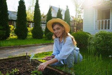 Portrait of a smiling gardener woman in the garden, preparing the soil and loosening it with a tool...
