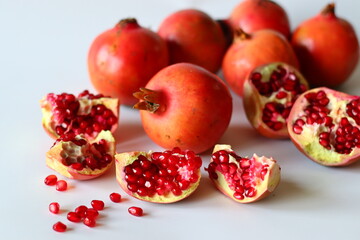 Pomegranate. Open fruit with glistening ruby red arils on a white surface, captured in soft natural light