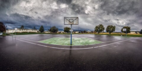 A basketball court under a brooding sky, suggesting a heavy rainstorm.