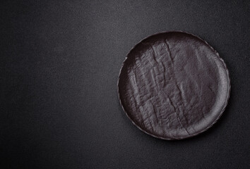 Empty round black plate for food, risotto or pasta. Empty plate on dark background