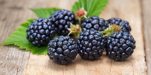 A collection of juicy, ripe blackberries sit on a weathered wooden background, ready to be enjoyed.