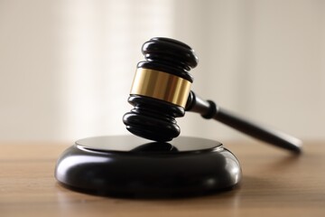 Judge's gavel on wooden table against light background, closeup