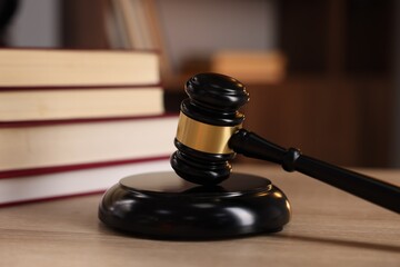 Judge's gavel and books on wooden table indoors, selective focus