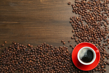 Aromatic coffee in cup and beans on wooden table, flat lay. Space for text