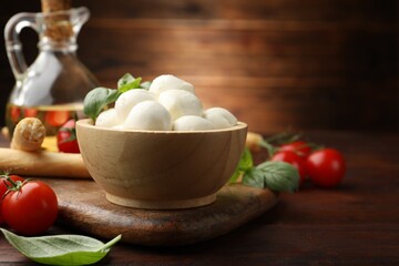 Tasty mozzarella cheese balls, breadsticks, tomatoes and basil on wooden table, closeup