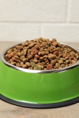 Dry pet food in feeding bowl on floor, closeup