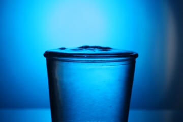 Fresh water in glass on blue gradient background, closeup. Backlit