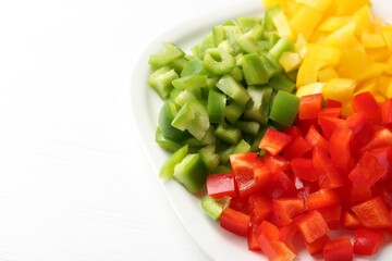 Pieces of fresh colorful bell peppers on white wooden table, closeup. Space for text