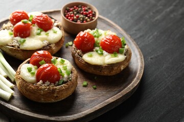 Tasty stuffed mushrooms served on black table, closeup