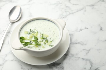 Tasty cucumber soup with dill and microgreens served on white marble table, closeup. Space for text