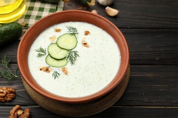 Tasty cucumber soup with dill, walnuts and ingredients on wooden table, closeup