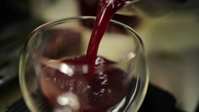 Slow motion berry tea pouring from pitcher into clear cocktail glass