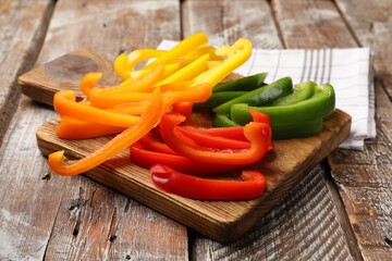Cut colorful bell peppers on wooden table, closeup