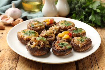 Tasty stuffed mushrooms and ingredients on wooden table, closeup