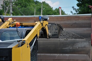 Loading soil with a tractor onto a truck. view of a working excavator