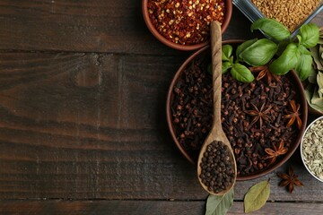 Different aromatic spices on wooden table, flat lay. Space for text