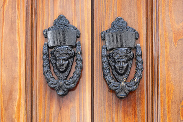 Triana, Seville, Andalusia, Spain. Antique brass door knockers on an old wooden door.