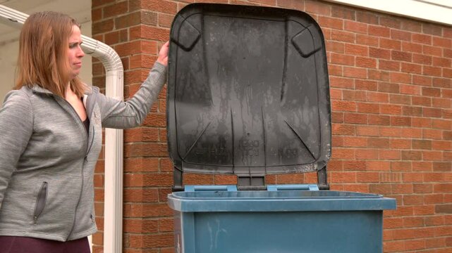 Girl closing lid to trash can slow motion
