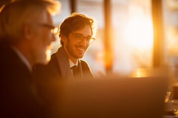 Young professionals receive mentoring from older colleagues, warm light and mutual focus.