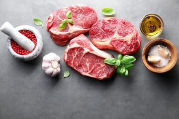 Pieces of raw beef meat and spices on grey table, flat lay. Space for text