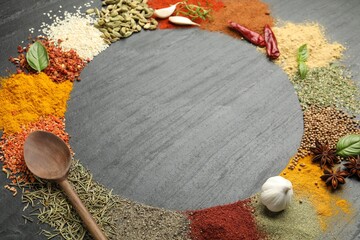 Different aromatic spices and spoon on dark textured table, t closeup . Space for text