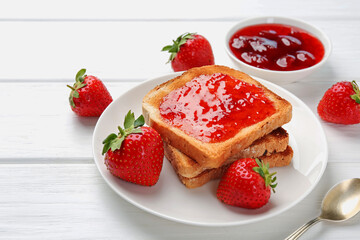 Toasts with tasty strawberry jam and fresh berries on white wooden table, closeup