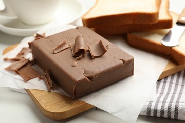 Block of tasty chocolate butter and bread slices on table, closeup