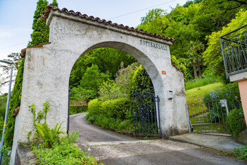 Obraz premium Old stone entrance gate in a green landscaped garden in Caslano, Switzerland
