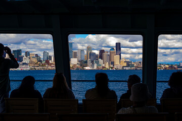 Silhouette of people on the Bainbridge Ferry approaching the Seattle skyline, Washington State, USA.