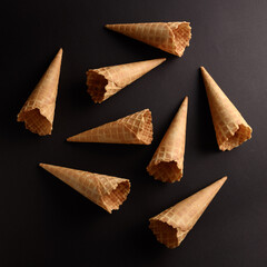 Waffle cones are neatly arranged on a dark surface, showcasing their crisp texture and ready for...