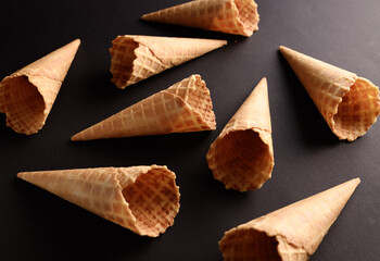 Waffle cones lay scattered on a dark background, inviting ice cream lovers to fill them with their...