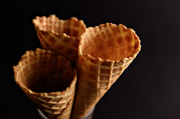Three empty waffle cones stand upright, ready for a scoop of ice cream or a sprinkle of toppings in a dessert shop