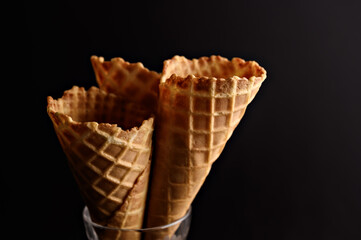 Three waffle cones stand upright in a glass, perfect for scooping ice cream, suggesting a sweet...