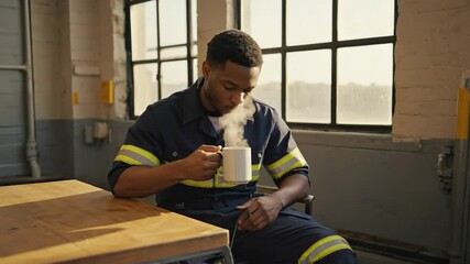 Man enjoying coffee in work attire at a bright industrial location