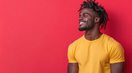Obraz premium A happy young man wearing a bright yellow t-shirt poses against a vibrant red background, showcasing joy and confidence in a playful manner that captivates the viewer's attention.