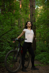 Beauty fun enjoying sport free woman biking on bicycle on path among green woods in a summer forest...