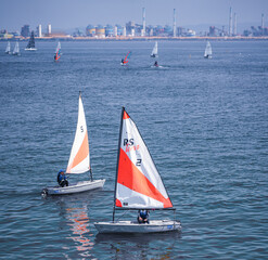 Fototapeta premium Pohang, Republic of Korea - July 02, 2023:Vibrant watersports scene in Pohang Bay. Dynamic watersports with sailboats and windsurfers.Sailboats, windsurfers and safety boats. 