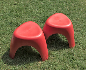 two red plastic seats are displayed outside on a lawn