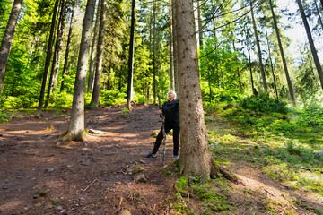 A hiker rests and looks up, leaning on his stick.