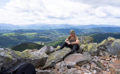 A man sat down to rest on the top of a mountain.