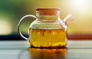 Transparent jug with herbal tea in the sun rays.