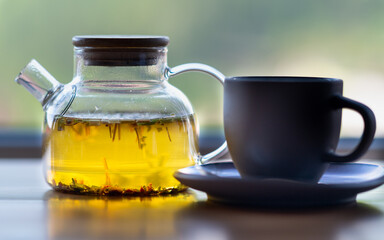 On the table there is a teapot with its contents and a cup and saucer.