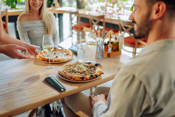 Waitress serving pizza to couple in pizzeria restaurant