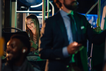 Young woman using tablet while riding public transport at night