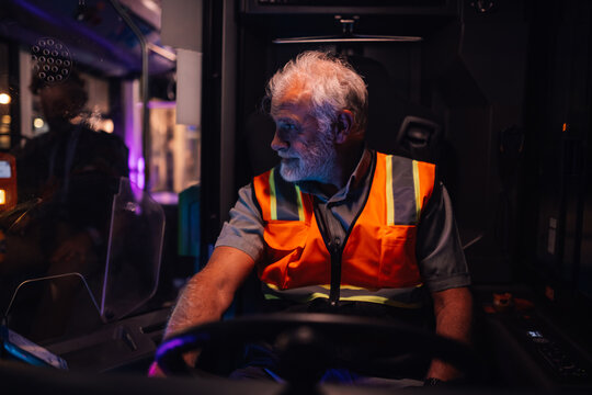 Senior bus driver steering vehicle at night, public transportation services